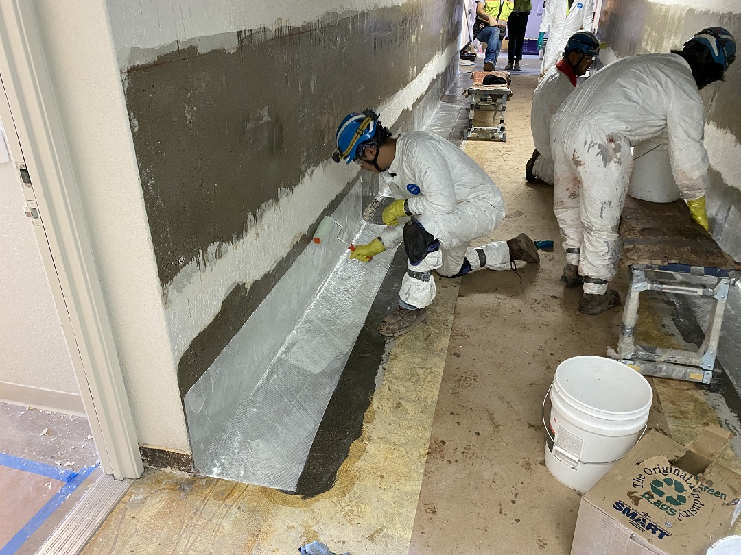 Photo 5: Note that the FRP applicator is using a roller to ensure intimate contact bewteen the saturated bidirectional glass fabric and primed concrete surface. 