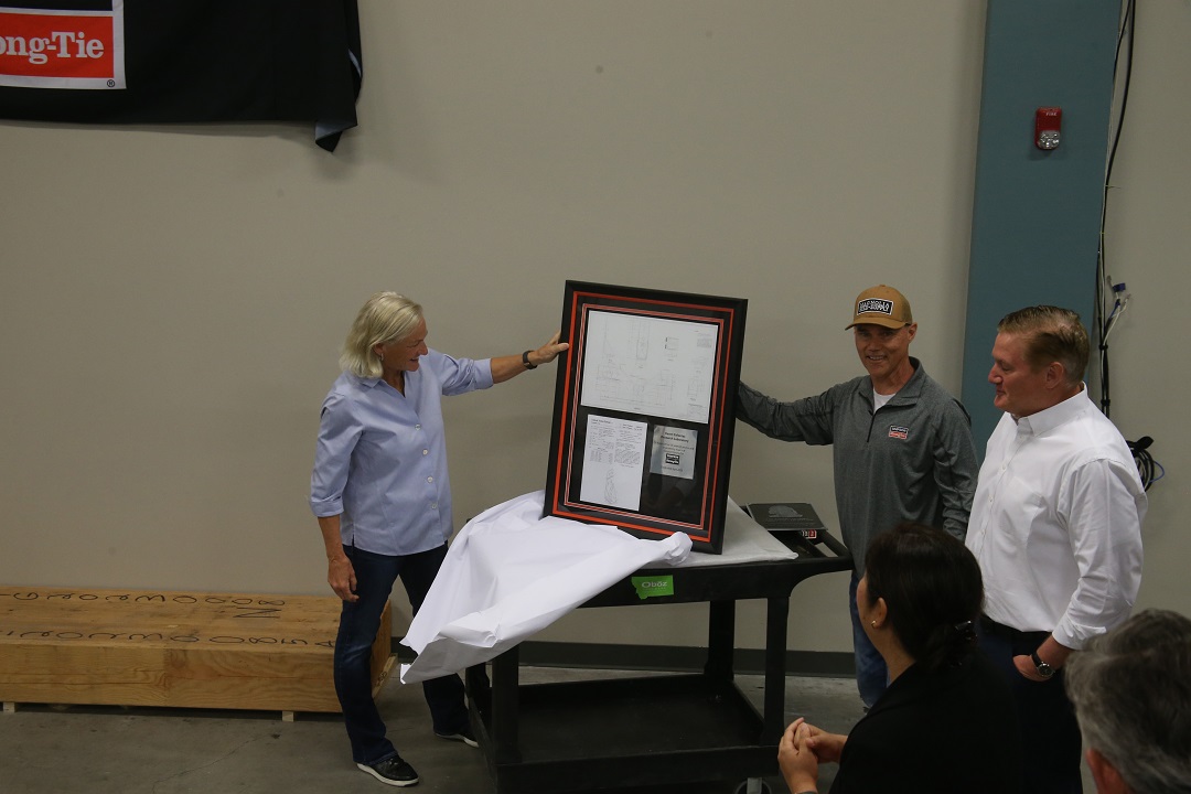 Simpson Strong-Tie David Huerta presenting Karen Colonias with a framed print of her original hand-drafted production drawing of an HD5A along with her first patent for that product